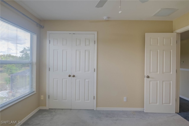 unfurnished bedroom featuring light carpet, a closet, and ceiling fan