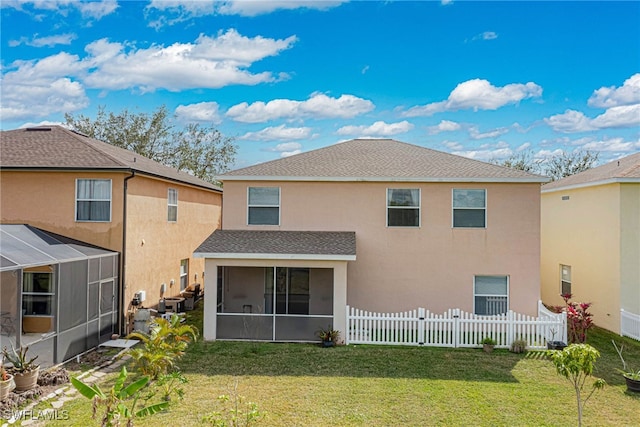 back of property featuring a sunroom and a lawn