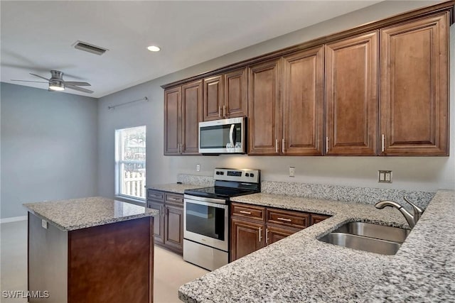 kitchen with ceiling fan, appliances with stainless steel finishes, light stone countertops, and sink