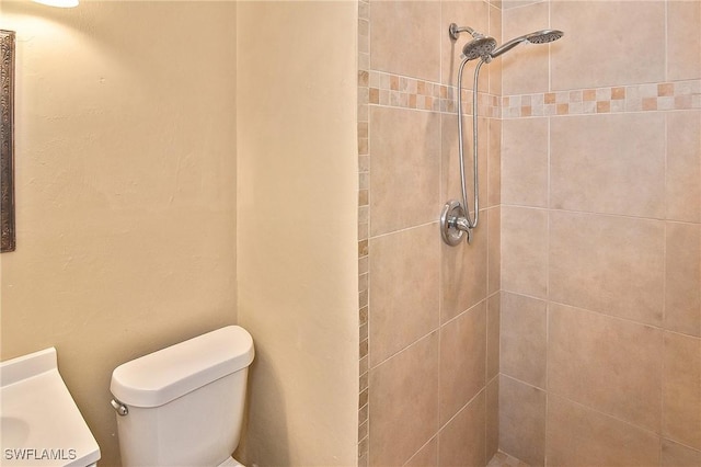 bathroom with toilet, vanity, and tiled shower