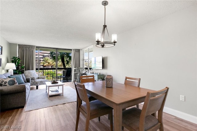 dining space with a chandelier, light hardwood / wood-style flooring, expansive windows, and a textured ceiling