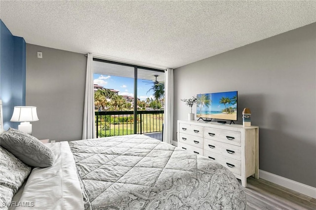 bedroom with expansive windows, hardwood / wood-style floors, a textured ceiling, and access to outside