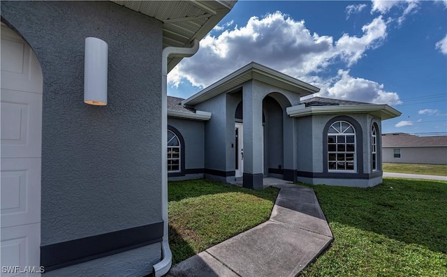 view of front of house with a garage, a front yard, and stucco siding