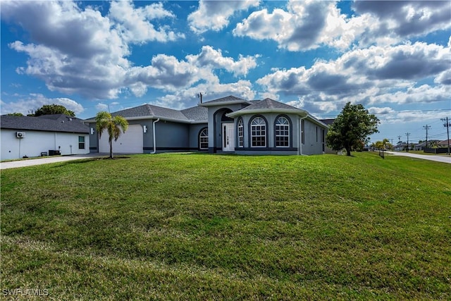 view of front facade with a garage, driveway, a front yard, and stucco siding