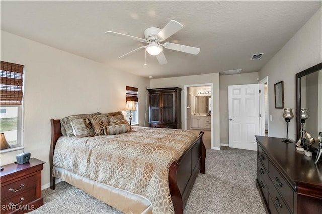 bedroom featuring connected bathroom, light colored carpet, and ceiling fan