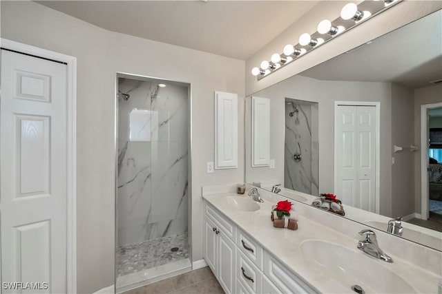 full bath with a sink, a marble finish shower, and double vanity