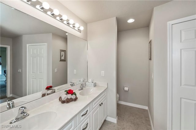 bathroom featuring baseboards, a sink, toilet, and tile patterned floors