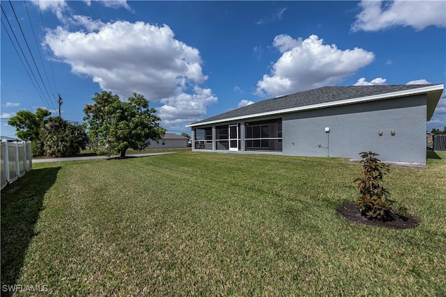 rear view of property featuring a sunroom, fence, stucco siding, and a yard