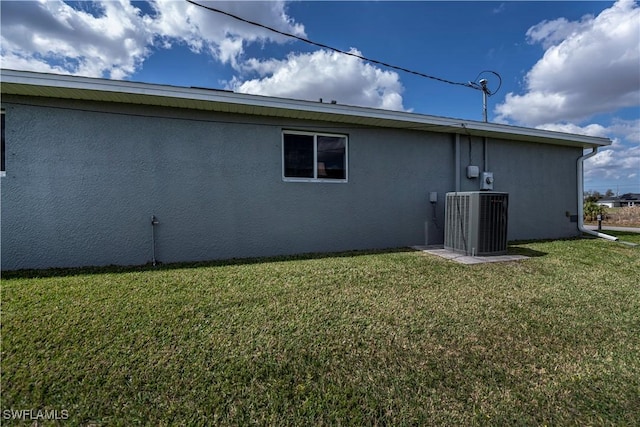 rear view of property with cooling unit, a lawn, and stucco siding