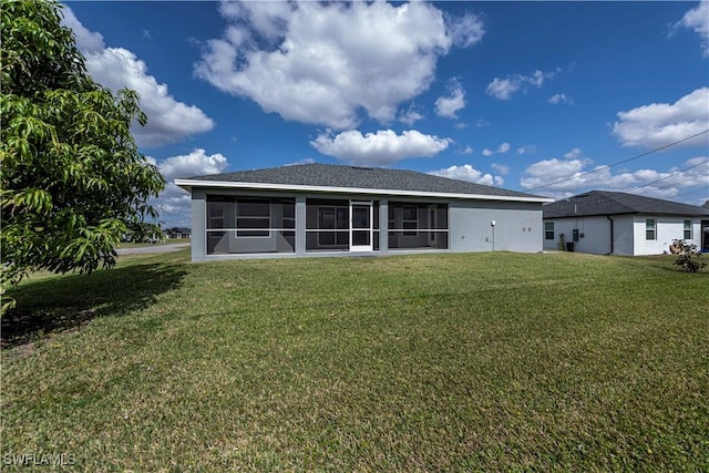 rear view of property featuring a yard, a sunroom, and stucco siding