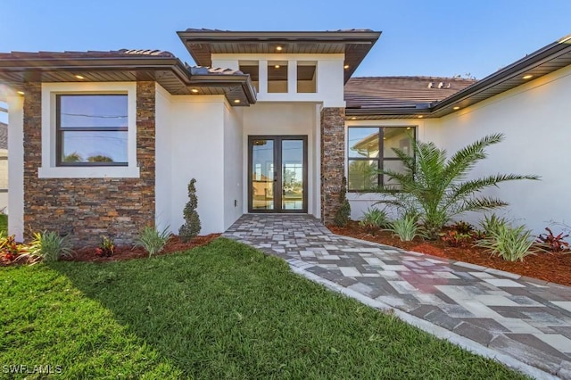 doorway to property with a lawn and french doors