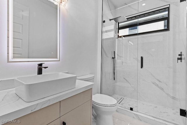 bathroom featuring vanity, toilet, and a shower with shower door