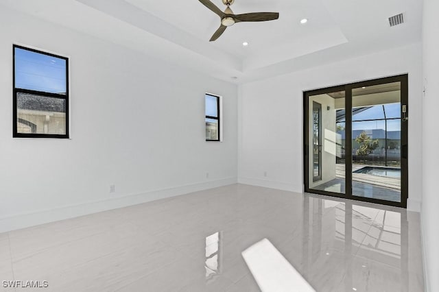 spare room with a raised ceiling and ceiling fan