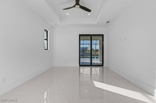 unfurnished room with ceiling fan and a raised ceiling