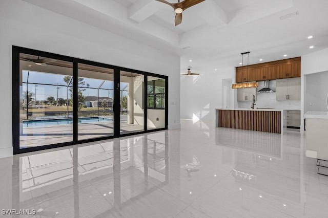 unfurnished living room featuring a towering ceiling, beamed ceiling, sink, coffered ceiling, and ceiling fan