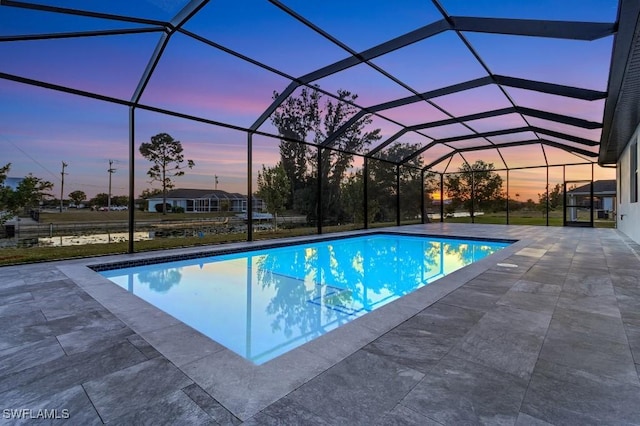 pool at dusk featuring a patio and glass enclosure