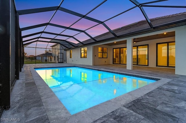 pool at dusk with a patio, ceiling fan, and glass enclosure