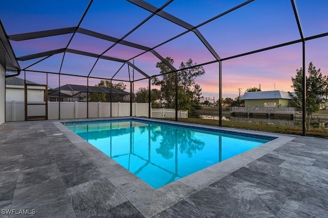 pool at dusk featuring a patio area and glass enclosure