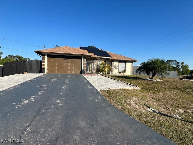 ranch-style house featuring a garage, a front lawn, and solar panels