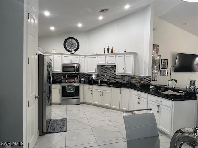 kitchen featuring stainless steel appliances, white cabinetry, lofted ceiling, and sink