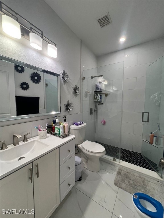 bathroom featuring vanity, toilet, and a shower with shower door