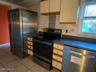 kitchen with dishwasher, light tile patterned flooring, decorative backsplash, and electric stove