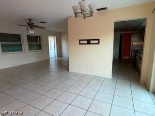 unfurnished room featuring ceiling fan with notable chandelier and light tile patterned flooring