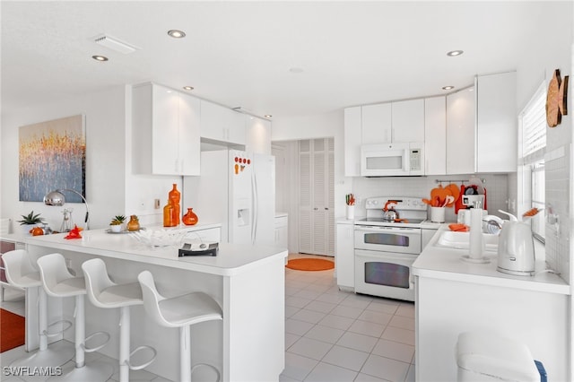 kitchen featuring white cabinetry, sink, white appliances, and kitchen peninsula