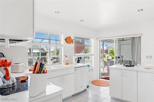 kitchen featuring sink, white cabinetry, light tile patterned floors, dishwasher, and decorative backsplash