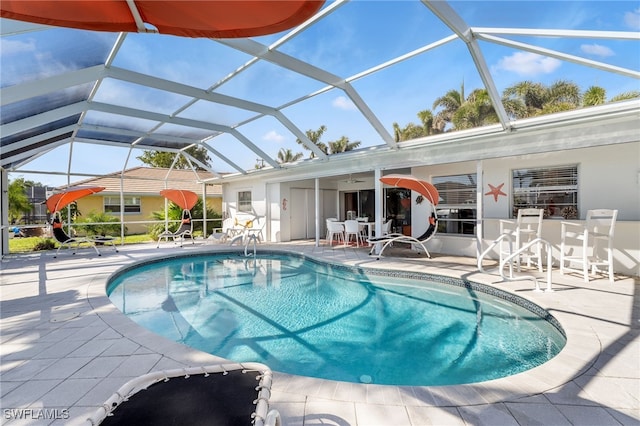 view of swimming pool featuring a patio, ceiling fan, and glass enclosure