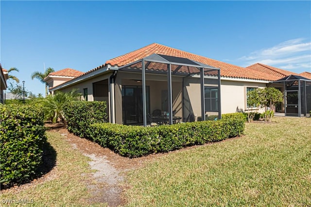 back of property featuring a lawn and glass enclosure