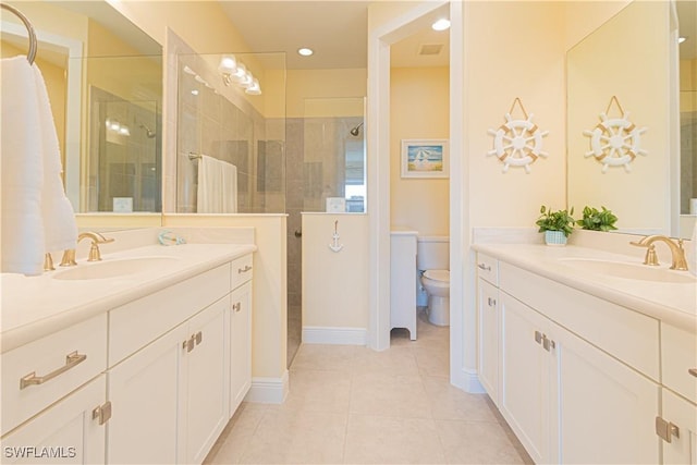 bathroom featuring tile patterned flooring, vanity, toilet, and tiled shower