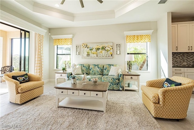 living room featuring crown molding, ceiling fan, a raised ceiling, and light tile patterned floors