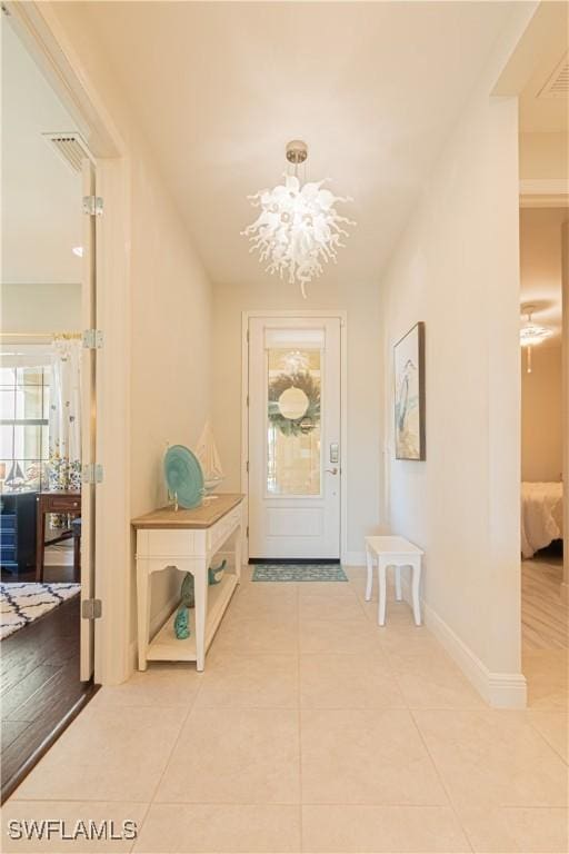 doorway to outside with tile patterned floors and an inviting chandelier