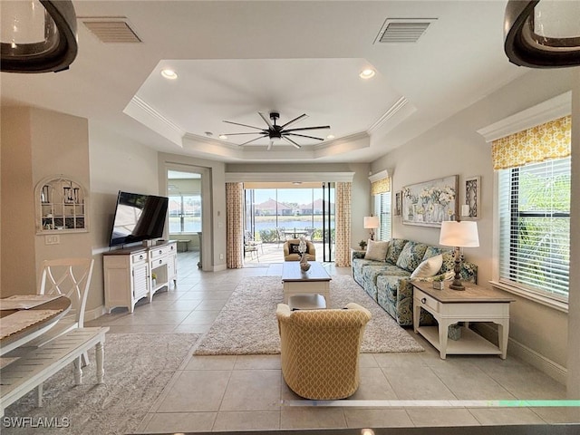 tiled living room featuring ceiling fan, ornamental molding, and a tray ceiling