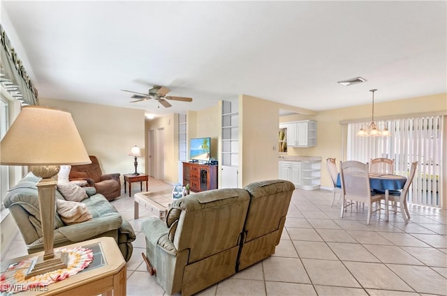 living room featuring ceiling fan with notable chandelier and light tile patterned flooring