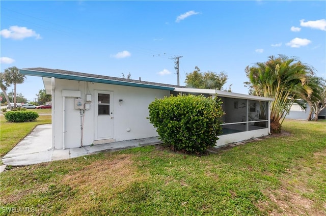 back of property with a sunroom and a lawn