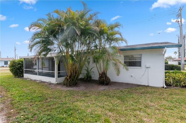 rear view of house featuring a sunroom and a lawn