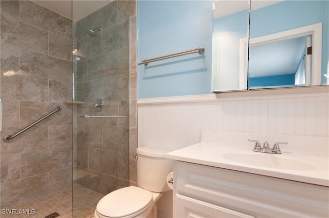 bathroom featuring a tile shower, vanity, and toilet