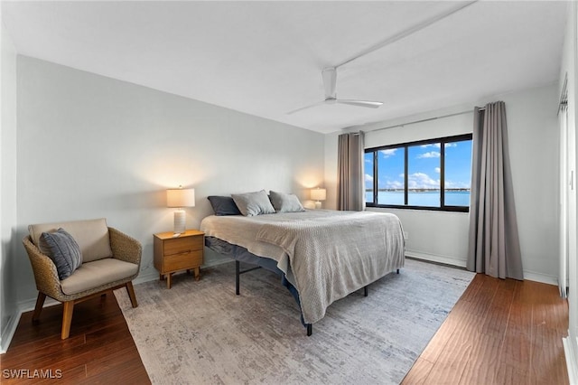 bedroom featuring a water view, ceiling fan, and wood finished floors