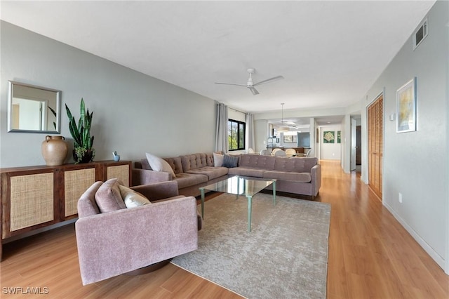 living area featuring ceiling fan, light wood-type flooring, visible vents, and baseboards