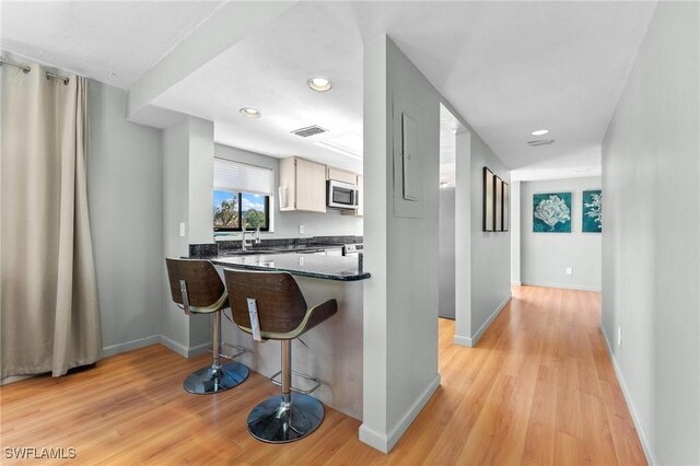 kitchen with appliances with stainless steel finishes, kitchen peninsula, light hardwood / wood-style floors, and white cabinets