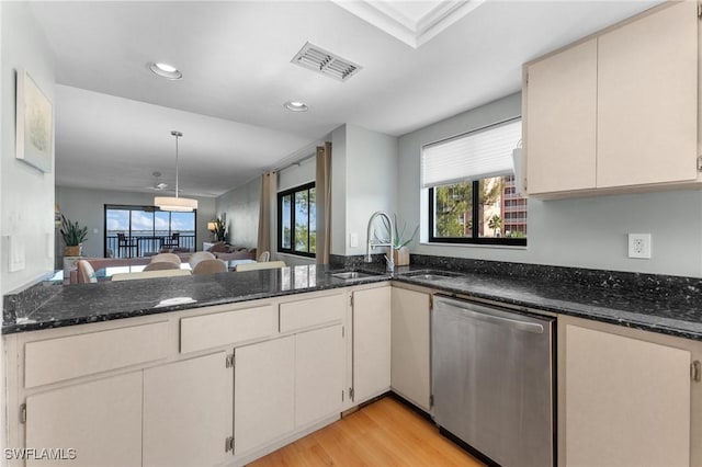 kitchen featuring a peninsula, visible vents, open floor plan, stainless steel dishwasher, and dark stone countertops