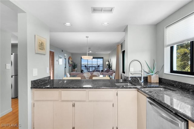 kitchen with stainless steel appliances, visible vents, open floor plan, a wealth of natural light, and dark stone counters