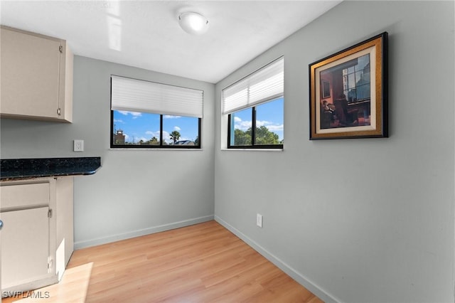 unfurnished dining area with light wood-style floors and baseboards