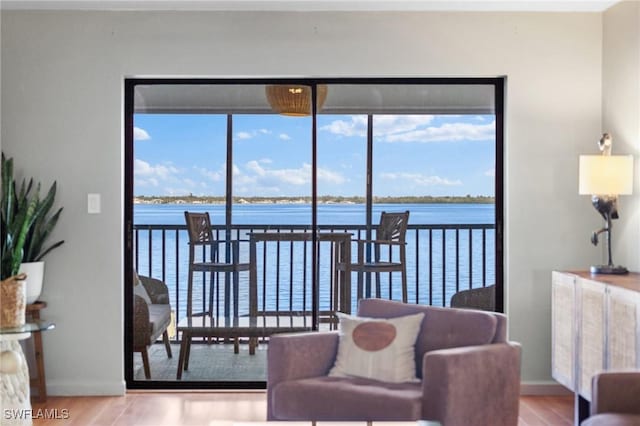 living room featuring light wood-type flooring, a water view, and baseboards