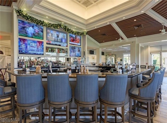 bar with a towering ceiling, ornamental molding, and light hardwood / wood-style floors