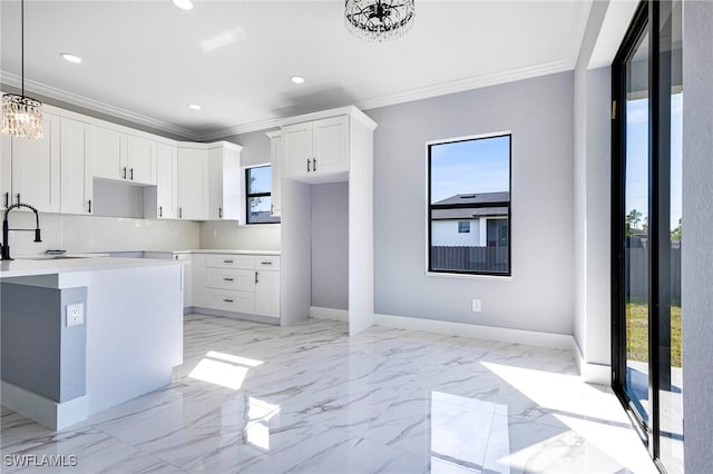 kitchen with pendant lighting, white cabinetry, sink, a chandelier, and ornamental molding