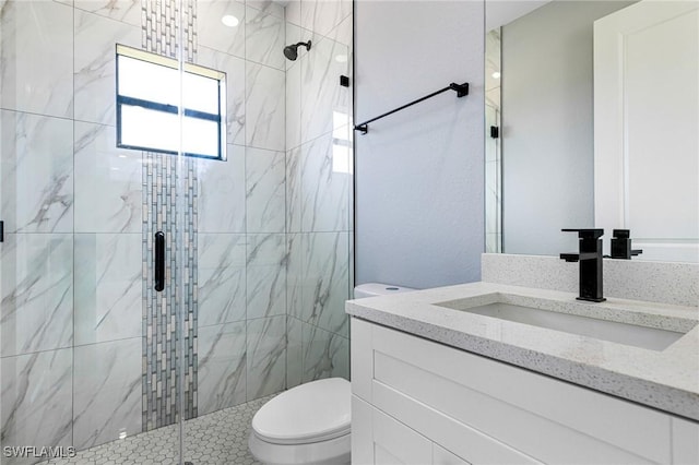 bathroom featuring vanity, toilet, and a shower with shower door