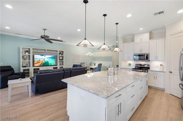 kitchen with hanging light fixtures, stainless steel appliances, a center island, ornamental molding, and white cabinets